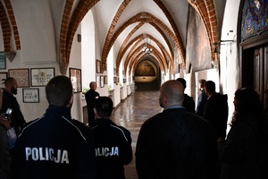 Policjanci i uczestnicy konferencji stoją na korytarzu klasztoru