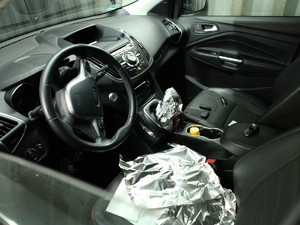 Wnętrze samochodu, zdjęcie zrobione od strony szyby kierowcy. Widać częściowo rozmontowaną okolicę dźwigni zmiany biegów.