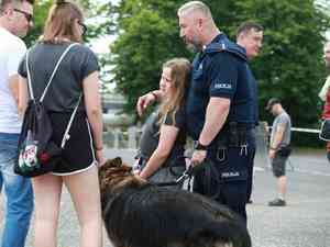 policjant z psem służbowym stoi z grupa osób