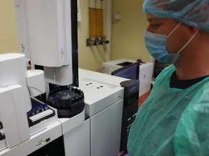 pracownik laboratorium przed maszyną z probówkami