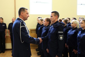 Komendant Wojewódzki Policji w Poznaniu insp. Piotr Mąka w galowym mundurze wita się z młodym nowo przyjętym policjantem