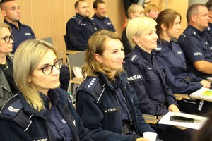 Policjantki w mundurach siedzą i słuchają prelekcji.