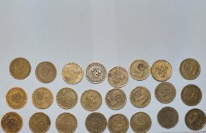 Kilkanaście starych monet leży na blacie.